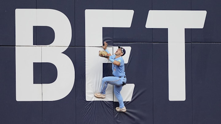 Toronto Blue Jays center fielder Daulton Varsho (25) climbs the center field wall to try a get to a ball hit by Los Angeles Angels left fielder Taylor Ward (not pictured) for a solo home run during the ninth inning at Rogers Centre on Aug 24.