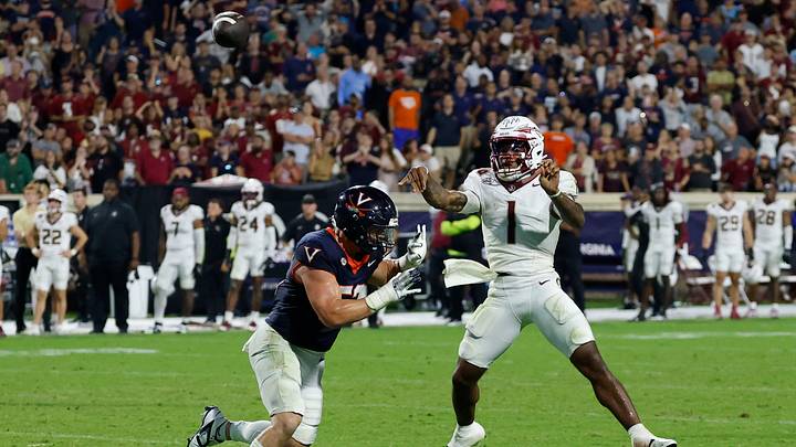 Sep 26, 2025; Charlottesville, Virginia, USA; Florida State Seminoles quarterback Tommy Castellanos (1) throws a game-tying touchdown pass in the final seconds of the fourth quarter as Virginia Cavaliers defensive lineman Daniel Rickert (52) chases at Scott Stadium. Mandatory Credit: Geoff Burke-Imagn Images Sep 26, 2025; Charlottesville, Virginia, USA; Florida State Seminoles quarterback Tommy Castellanos (1) throws a game-tying touchdown pass in the final seconds of the fourth quarter as Virginia Cavaliers defensive lineman Daniel Rickert (52) chases at Scott Stadium. Mandatory Credit: Geoff Burke-Imagn Images
