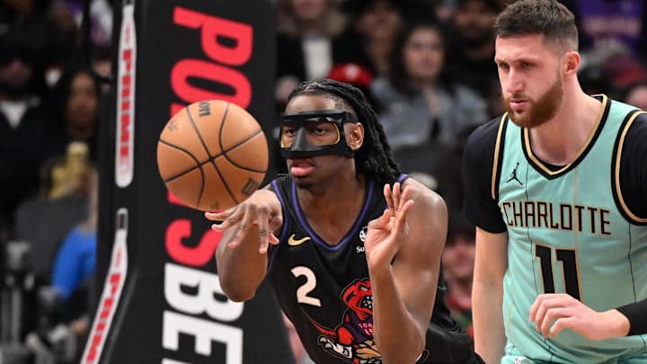 Mar 28, 2025; Toronto, Ontario, CAN;  Toronto Raptors forward Jonathan Mogbo (2) passes the ball away from Charlotte Hornets center Jusuf Nurkic (11) in the second half at Scotiabank Arena. Mandatory Credit: Dan Hamilton-Imagn Images