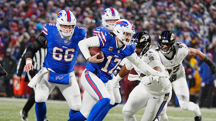 Buffalo Bills quarterback Josh Allen runs with the ball trying to avoid the reach of Baltimore Ravens star Nnamdi Madubuike.