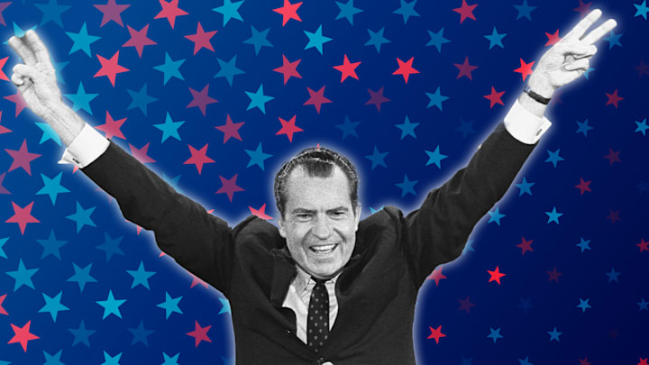 Richard Nixon flashes his trademark “victory” sign.