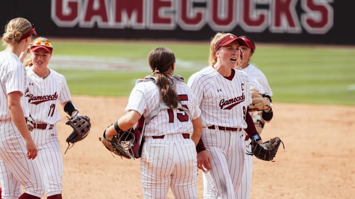 South Carolina softball's Sam Gress screams in celebration during a game while her teammates hive-five around her.