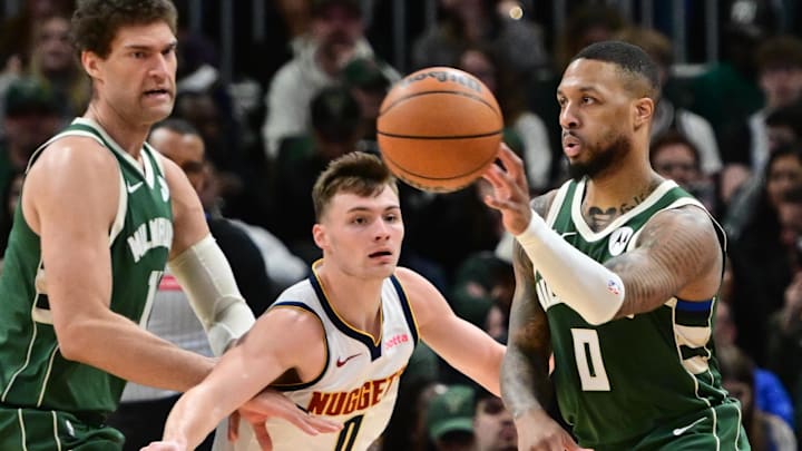 Feb 27, 2025; Milwaukee, Wisconsin, USA; Milwaukee Bucks guard Damian Lillard (0) passes the ball away from Denver Nuggets forward Christian Braun (0) in the third quarter at Fiserv Forum. Mandatory Credit: Benny Sieu-Imagn Images