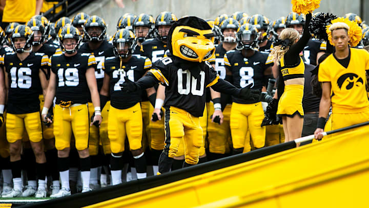 Iowa Hawkeyes players hold hands as they get ready to swarm onto the field with the University of Iowa mascot.