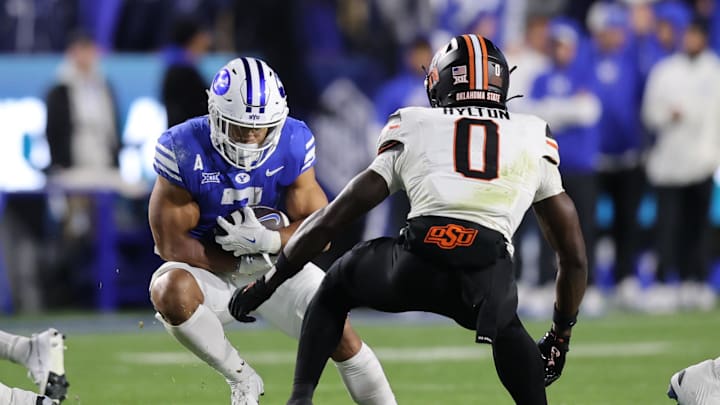 Oct 18, 2024; Provo, Utah, USA; Brigham Young Cougars running back Hinckley Ropati (7) runs against Oklahoma State Cowboys safety Kobe Hylton (0) during the second quarter at LaVell Edwards Stadium. Mandatory Credit: Rob Gray-Imagn Images