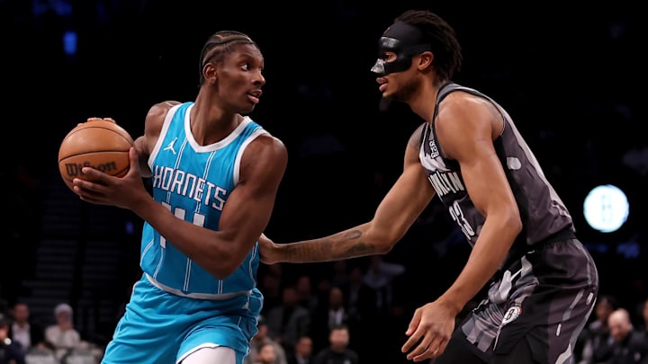 Feb 10, 2025; Brooklyn, New York, USA; Charlotte Hornets forward Moussa Diabate (14) controls the ball against Brooklyn Nets center Nic Claxton (33) during the first quarter at Barclays Center. Mandatory Credit: Brad Penner-Imagn Images