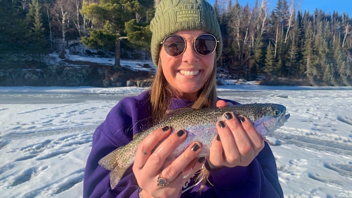 Tashina Dunham holds a rainbow trout she caught through the ice on a reclaimed lake managed exclusively for trout.