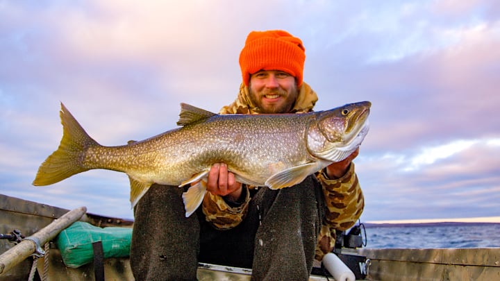 The author holds a 14-pound Lake Superior lake trout caught while jigging from a small boat on a rare warm, calm January day—proof that winter sometimes rewards dedication.