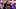 "Two people interact closely at an outdoor event with tents in the background, one gently touching the other's cheek." "Two people interact closely at an outdoor event with tents in the background, one gently touching the other's cheek."