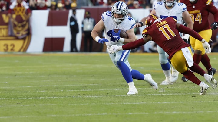 Dallas Cowboys running back Hunter Luepke runs with the ball as Washington Commanders safety Jeremy Chinn defends at Northwest Stadium. 