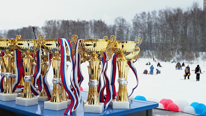 Trophies line the stage as anglers compete on the ice during a midwinter fishing derby.