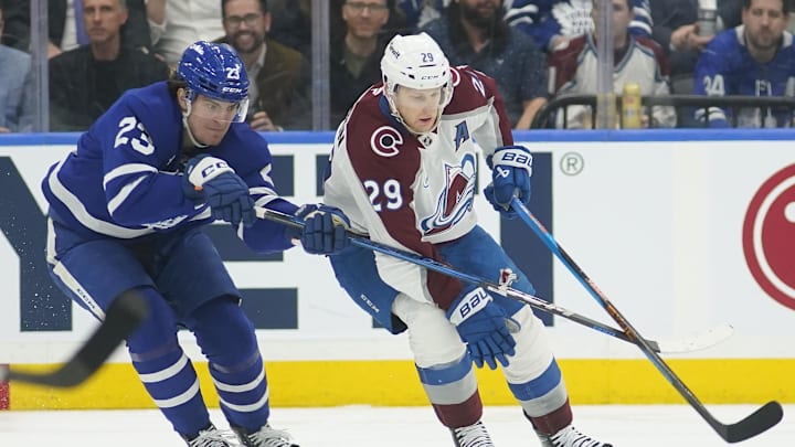 Mar 19, 2025; Toronto, Ontario, CAN; Toronto Maple Leafs forward Matthew Knies (23) tries to slow up Colorado Avalanche forward Nathan MacKinnon (29) during the second period at Scotiabank Arena. Mandatory Credit: John E. Sokolowski-Imagn Images