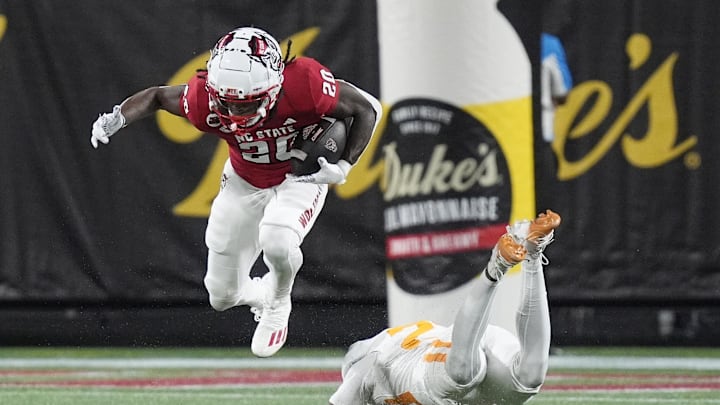 Sep 7, 2024; Charlotte, North Carolina, USA; North Carolina State Wolfpack running back Hollywood Smothers (20) evades Tennessee Volunteers defensive back Boo Carter (23) during the second quarter at the Dukes Mayo Classic at Bank of America Stadium. Mandatory Credit: Jim Dedmon-Imagn Images