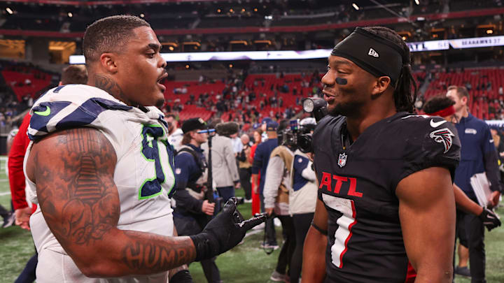 Dec 7, 2025; Atlanta, Georgia, USA; Seattle Seahawks defensive tackle Byron Murphy II (91) talks to Atlanta Falcons running back Bijan Robinson (7) after a game at Mercedes-Benz Stadium.