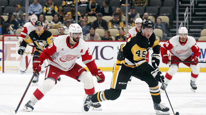 Oct 1, 2024; Pittsburgh, Pennsylvania, USA;  Pittsburgh Penguins defenseman Harrison Brunicke (45) handles the puck ahead of Detroit Red Wings center Joe Veleno (90) during the second period at PPG Paints Arena. Mandatory Credit: Charles LeClaire-Imagn Images