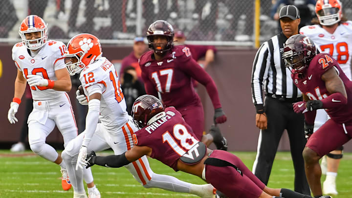 Nov 9, 2024; Blacksburg, Virginia, USA;  .Virginia Tech Hokies safety Mose Phillips III (18) dives to tackle Clemson Tigers cornerback Corian Gipson (12) during the first quarter at Lane Stadium. Mandatory Credit: Brian Bishop-Imagn Images