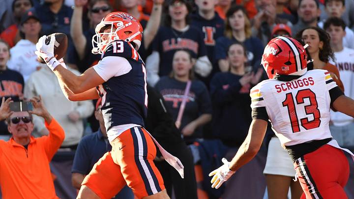Nov 15, 2025; Champaign, Illinois, USA; Illinois Fighting Illini wide receiver Hudson Clement (13) catches a touchdown pass as Maryland Terrapins defensive back Lavain Scruggs (13) pursues during the first half at Memorial Stadium. Mandatory Credit: Ron Johnson-Imagn Images