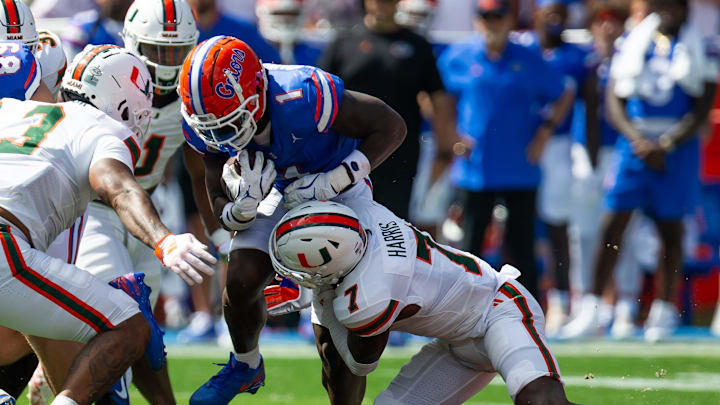 Florida Gators running back Montrell Johnson Jr. (1) finds a hole as Miami Hurricanes defensive back Jaden Harris (7) tackles him during the season opener at Ben Hill Griffin Stadium in Gainesville, FL on Saturday, August 31, 2024 against the University of Miami Hurricanes in the first half. [Doug Engle/Gainesville Sun]