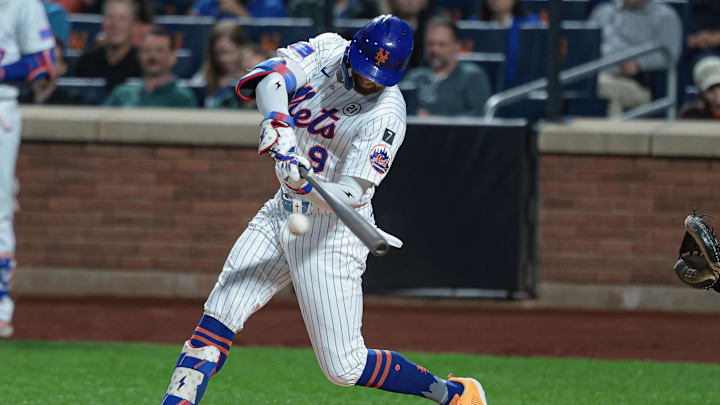 A baseball player in a white and blue uniform wearing a blue helmet while swinging a gray baseball bat. A baseball player in a white and blue uniform wearing a blue helmet while swinging a gray baseball bat.