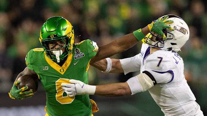 Oregon’s Jordon Davison, left, stiff arms James Madison’s Jacob Thomas for a gain during the second quarter Autzen Stadium in Eugene Dec. 20, 2025.