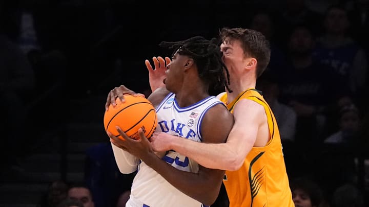 Mar 22, 2024; Brooklyn, NY, USA; Duke Blue Devils forward Mark Mitchell (25) grabs a rebound over Vermont Catamounts forward Nick Fiorillo (32) in the first round of the 2024 NCAA Tournament at the Barclays Center. Mandatory Credit: Robert Deutsch-Imagn Images