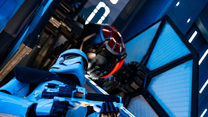 A First Order Stormtrooper stands guard in a Star Destroyer hangar bay beneath a docked TIE fighter in Star Wars: Rise of the Resistance, the groundbreaking new attraction opening Dec. 5, 2019, inside Star Wars: Galaxy’s Edge at Disney’s Hollywood Studios in Florida and Jan. 17, 2020, at Disneyland Park in California. Guests enter the hangar bay after their ship is caught in the Star Destroyer’s tractor beam. (Matt Stroshane, photographer)