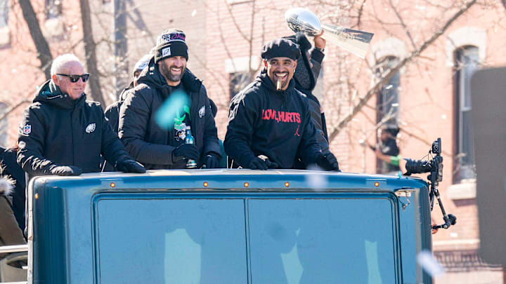 Philadelphia Eagles owner, Jeffrey Lurie, left, joins head coach Nick Sirianni and quarterback Jalen Hurts atop one of the team buses during the Super Bowl 59 victory parade.
