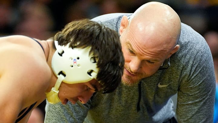 Penn State head coach Cael Sanderson talks to Nittany Lions wrestler PJ Duke during a match against Iowa.
