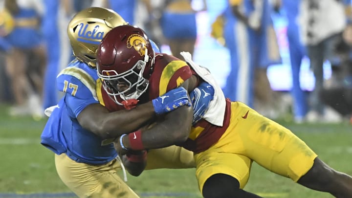 Nov 23, 2024; Pasadena, California, USA; USC Trojans running back Woody Marks (4) tries to break a tackle by UCLA Bruins linebacker Jalen Woods (17) during the third quarter at the Rose Bowl. Mandatory Credit: Robert Hanashiro-Imagn Images