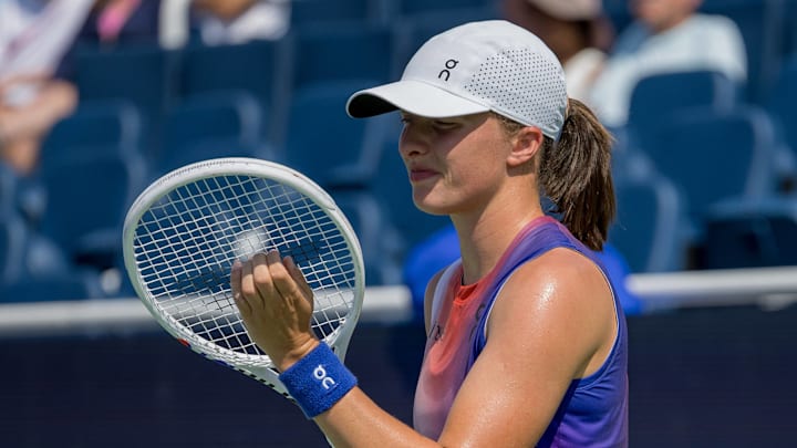 Iga Swiatek adjusts her tennis racket strings during a match at the Cincinnati Open.
