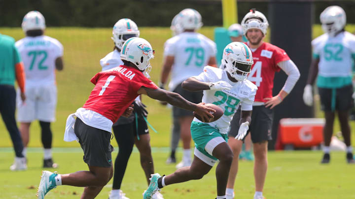 Miami Dolphins quarterback Tua Tagovailoa (1) handoffs the football to running back De'Von Achane (28) during mandatory minicamp at Hard Rock Stadium. Miami Dolphins quarterback Tua Tagovailoa (1) handoffs the football to running back De'Von Achane (28) during mandatory minicamp at Hard Rock Stadium.