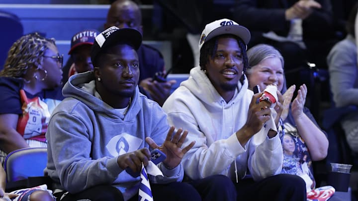 May 16, 2025; Washington, District of Columbia, USA; Washington Commanders wide receiver Deebo Samuels (L) and Commanders quarterback Jayden Daniels (R) wave to the crowd from courts wide during the game between the Washington Mystics and Atlanta Dream at CareFirst Arena. Mandatory Credit: Geoff Burke-Imagn Images