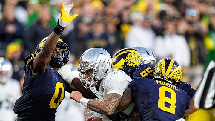 Michigan defensive end Derrick Moore (8), defensive lineman Mason Graham (55) and defensive end Josaiah Stewart (0) tackle Oregon quarterback Dillon Gabriel (8) during the second half at Michigan Stadium in Ann Arbor on Saturday, Nov. 2, 2024.