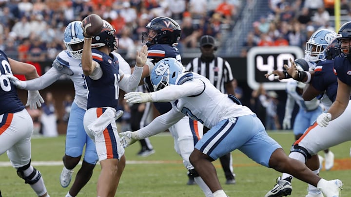 Oct 26, 2024; Charlottesville, Virginia, USA; Virginia Cavaliers quarterback Anthony Colandrea (10) prepares to pass the ball prior to being hit by North Carolina Tar Heels defensive end Kaimon Rucker (7) during the first half at Scott Stadium.