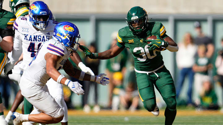 Nov 30, 2024; Waco, Texas, USA;  Baylor Bears running back Bryson Washington (30) runs the ball as Kansas Jayhawks safety Jalen Dye (14) defends during the second half at McLane Stadium. Mandatory Credit: Chris Jones-Imagn Images