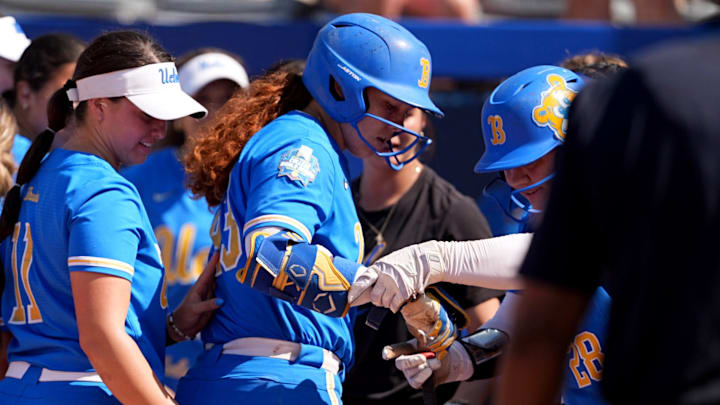 UCLA's Alexis Ramirez (28) helps Megan Grant (43) touch home plate after a home run in the 7th inning of the Women's College World Series softball game between the UCLA Bruins and the Tennessee Volunteers at Devon Park in Oklahoma City, Sunday, June, 1, 2025.