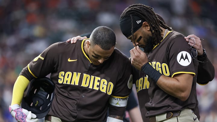 Apr 20, 2025; Houston, Texas, USA;San Diego Padres third baseman Manny Machado (13) and right fielder Fernando Tatis Jr. (23) pray for San Diego Padres designated hitter Luis Arraez (4) after he colliding with Houston Astros first baseman Christian Walker (8) (not pictured )on the first base line in the first inning at Daikin Park.Arraez was carted off the field . Mandatory Credit: Thomas Shea-Imagn Images
