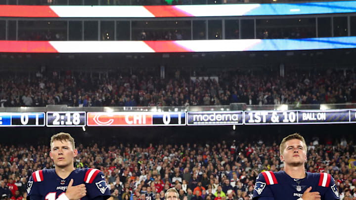 New England Patriots quarterbacks Mac Jones (left), and Bailey Zappe (right) stand at attention before a game vs. Chicago Bears at Gillette Stadium.