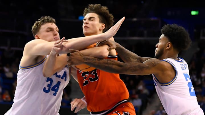 Feb 21, 2026; Los Angeles, California, USA; Illinois guard Keaton Wagler (23) tries to drive to the basket between UCLA forward Tyler Bilodeau (34) and UCLA guard Donovan Dent (2) during the second half at Pauley Pavilion presented by Wescom Financial. Mandatory Credit: Robert Hanashiro-Imagn Images