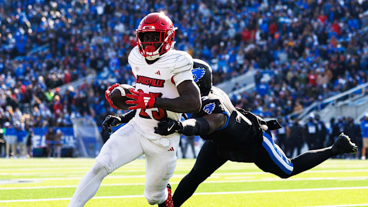 Nov 30, 2024; Lexington, Kentucky, USA; Louisville Cardinals running back Isaac Brown (25) runs the ball against Kentucky Wildcats defensive back Alex Afari Jr. (3) during the first quarter at Kroger Field. 