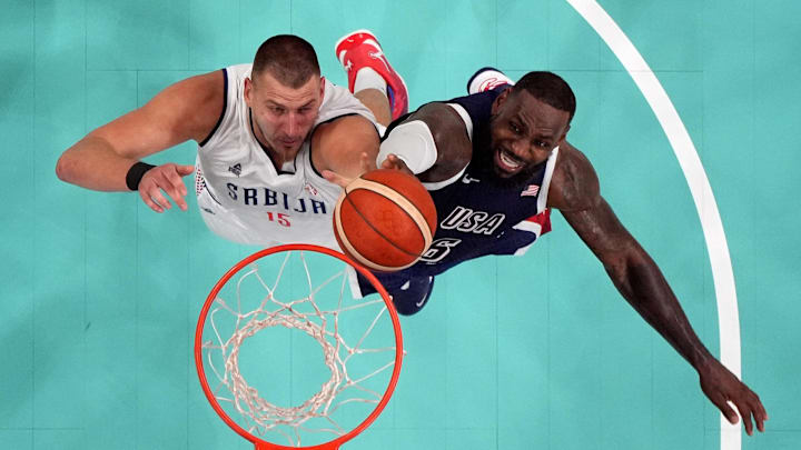 Jul 28, 2024; Villeneuve-d'Ascq, France; Serbia power forward Nikola Jokic (15) and United States guard Lebron James (6) jump for a rebound in the fourth quarter during the Paris 2024 Olympic Summer Games at Stade Pierre-Mauroy. Mandatory Credit: John David Mercer-Imagn Images