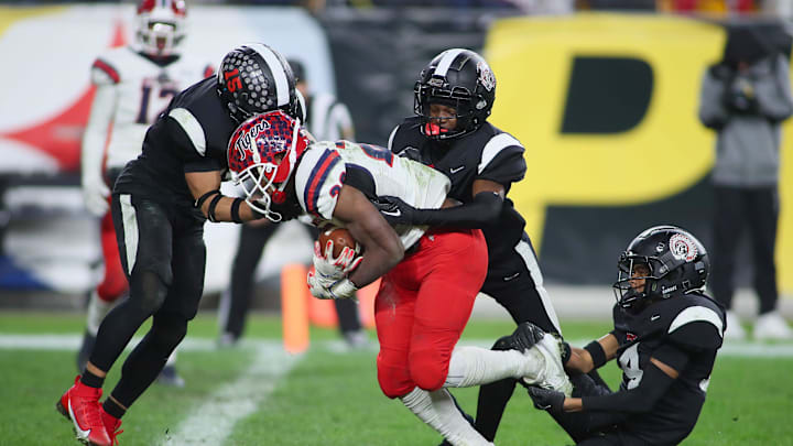 Aliquippa's QaLil Goode (14), Gavin Wilcox (13), and Arison Walker (15) attempt to hold back McKeesport's Kemon Spell (20) from scoring a touchdown during the second half of the WPIAL 4A Championship game Friday evening at Acrisure Stadium in Pittsburgh, PA.