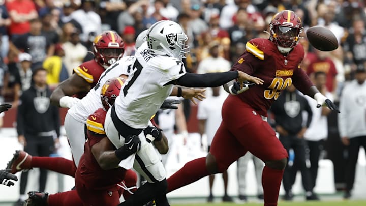 Sep 21, 2025; Landover, Maryland, USA; Las Vegas Raiders quarterback Geno Smith (7) passes the ball while being tackled by Washington Commanders nose tackle Daron Payne (94) during the second quarter at Northwest Stadium. Mandatory Credit: Geoff Burke-Imagn Images