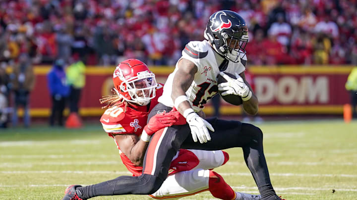 Dec 21, 2024; Kansas City, Missouri, USA; Houston Texans wide receiver Nico Collins (12) runs the ball as Kansas City Chiefs safety Justin Reid (20) makes the tackle during the first half at GEHA Field at Arrowhead Stadium. Mandatory Credit: Denny Medley-Imagn Images