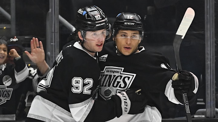 Mar 22, 2025; Los Angeles, California, USA; Los Angeles Kings defenseman Brandt Clarke (92) and left wing Trevor Moore (12) celebrate after scoring against the Carolina Hurricanes during the second period at Crypto.com Arena. Mandatory Credit: Jonathan Hui-Imagn Images