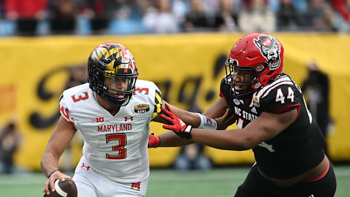 Dec 30, 2022; Charlotte, NC, USA; Maryland Terrapins quarterback Taulia Tagovailoa (3) scrambles as North Carolina State Wolfpack defensive lineman Brandon Cleveland (44) defends in the fourth quarter in the 2022 Duke's Mayo Bowl at Bank of America Stadium. Mandatory Credit: Bob Donnan-Imagn Images