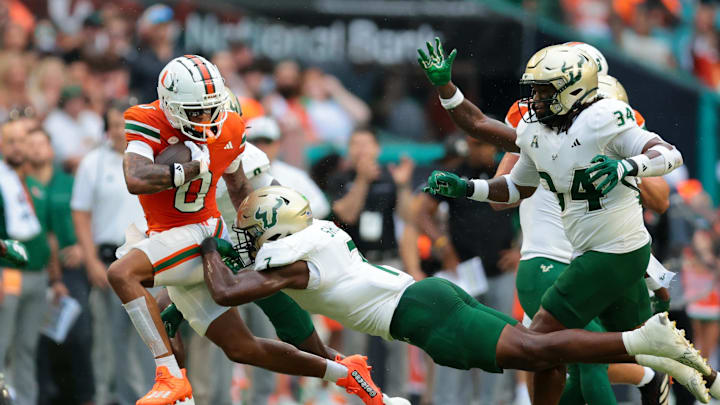 Sep 13, 2025; Miami Gardens, Florida, USA; Miami Hurricanes wide receiver Keelan Marion (0) runs with the football against South Florida Bulls linebacker Jhalyn Shuler (7) during the first quarter at Hard Rock Stadium. Mandatory Credit: Sam Navarro-Imagn Images