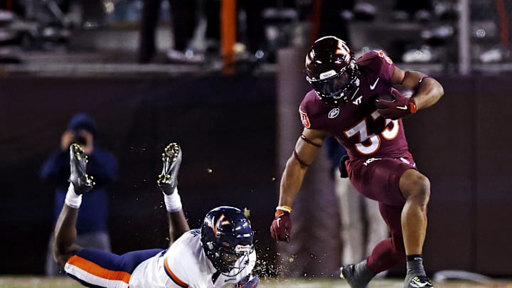 Nov 30, 2024; Blacksburg, Virginia, USA; Virginia Tech Hokies running back Bhayshul Tuten (33) runs the ball against Virginia Cavaliers defensive end Miles Greene (14) during the fourth quarter at Lane Stadium. Mandatory Credit: Peter Casey-Imagn Images