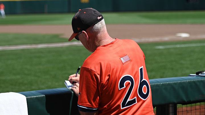 Jun 14, 2024; Omaha, NE, USA;  Virginia Cavalier head coach Brian O'Connor makes notes during a break in the game against the North Carolina Tar Heels during the seventh inning at Charles Schwab Filed Omaha. Mandatory Credit: Steven Branscombe-Imagn Images