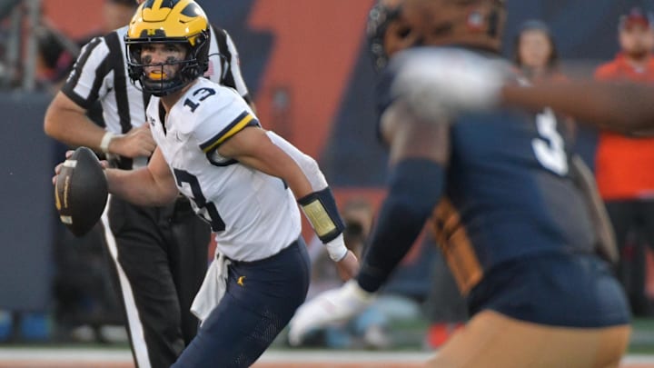 Oct 19, 2024; Champaign, Illinois, USA;  Michigan Wolverines quarterback Jack Tuttle (13) runs with the ball against Illinois Fighting Illini linebacker Alec Bryant (3) during the second half at Memorial Stadium. Mandatory Credit: Ron Johnson-Imagn Images